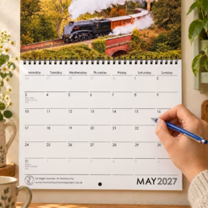 Close-up of the 2027 railway calendar showing writing space with a hand holding a pen